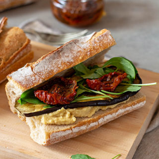Bocadillos saludables de hummus, berenjena, tomate seco y rúcula